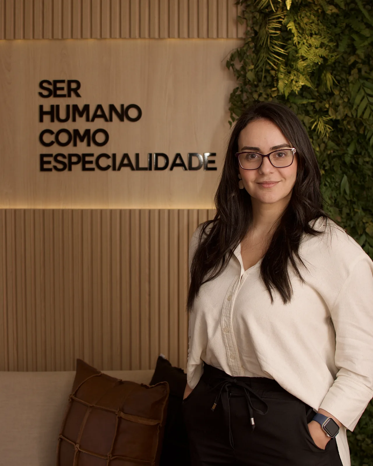 Daniela Filippo, psicóloga clínica, sorrindo, em ambiente de madeira com parede verde.